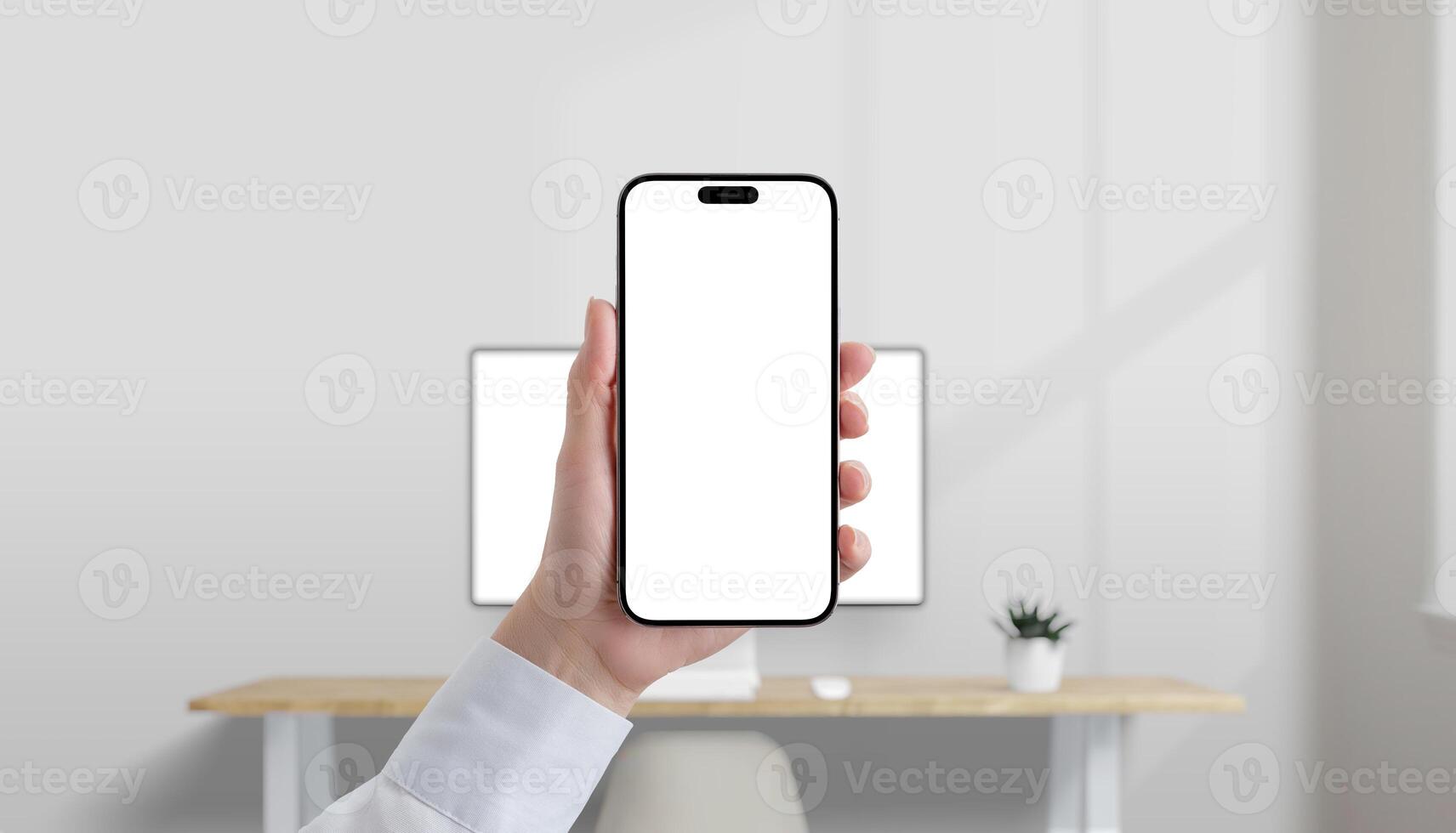 Smartphone with blank white screen held in hand in modern office, desktop computer in background, perfect for mobile UI mockup photo