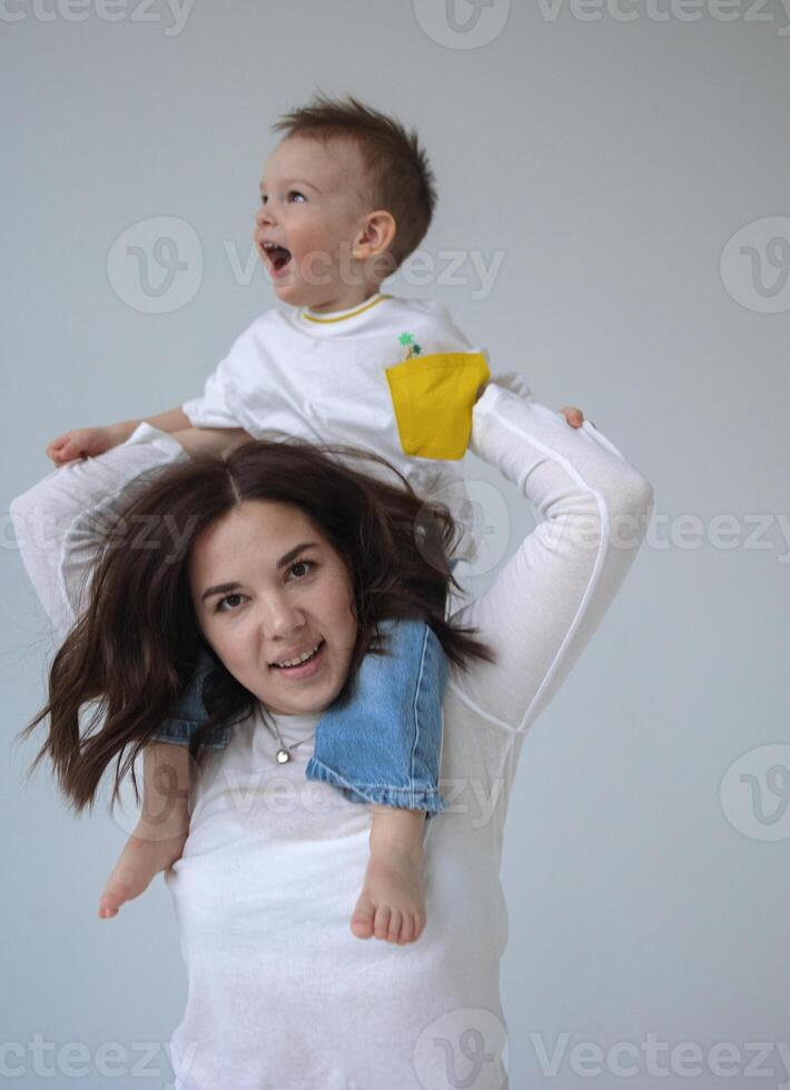 A young mother and her two-year-old son, who is sitting on her shoulders, spend time together photo