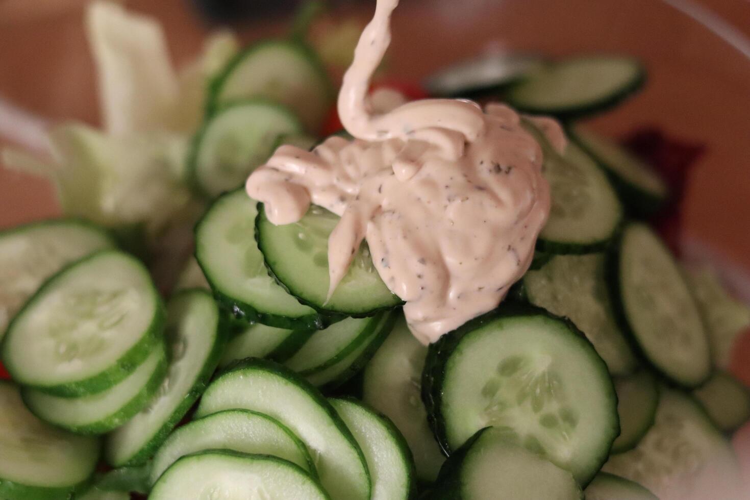 Cucumber slices topped with creamy dressing in a salad bowl ready for serving at a casual gathering photo