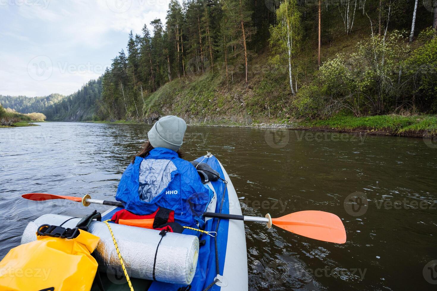 An adventurous kayaker is enthusiastically exploring a serene river, navigating through a stunning natural landscape filled with lush greenery, picturesque views, and a tranquil environment photo