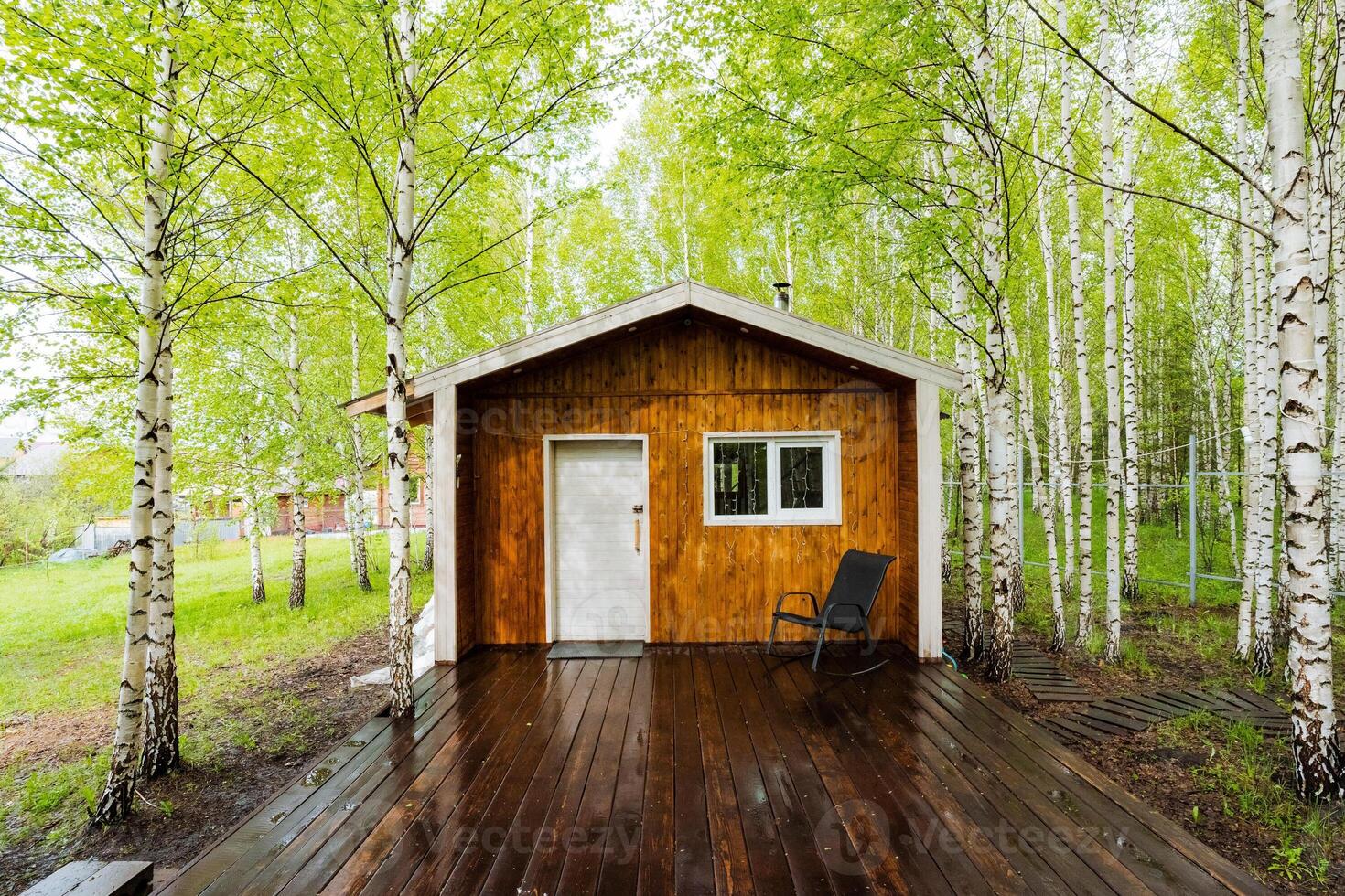 Nestled in the heart of a lush, tranquil forest stands a quaint small house featuring a charming wooden deck, ideal for enjoying the serene surroundings and natural beauty of nature photo