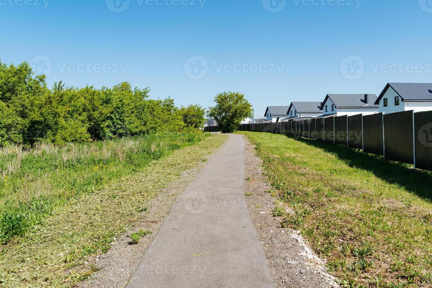 A winding path elegantly meanders through a lush, vibrant field situated in the beautiful countryside, where charming rustic houses and breathtaking views create an idyllic rural setting photo