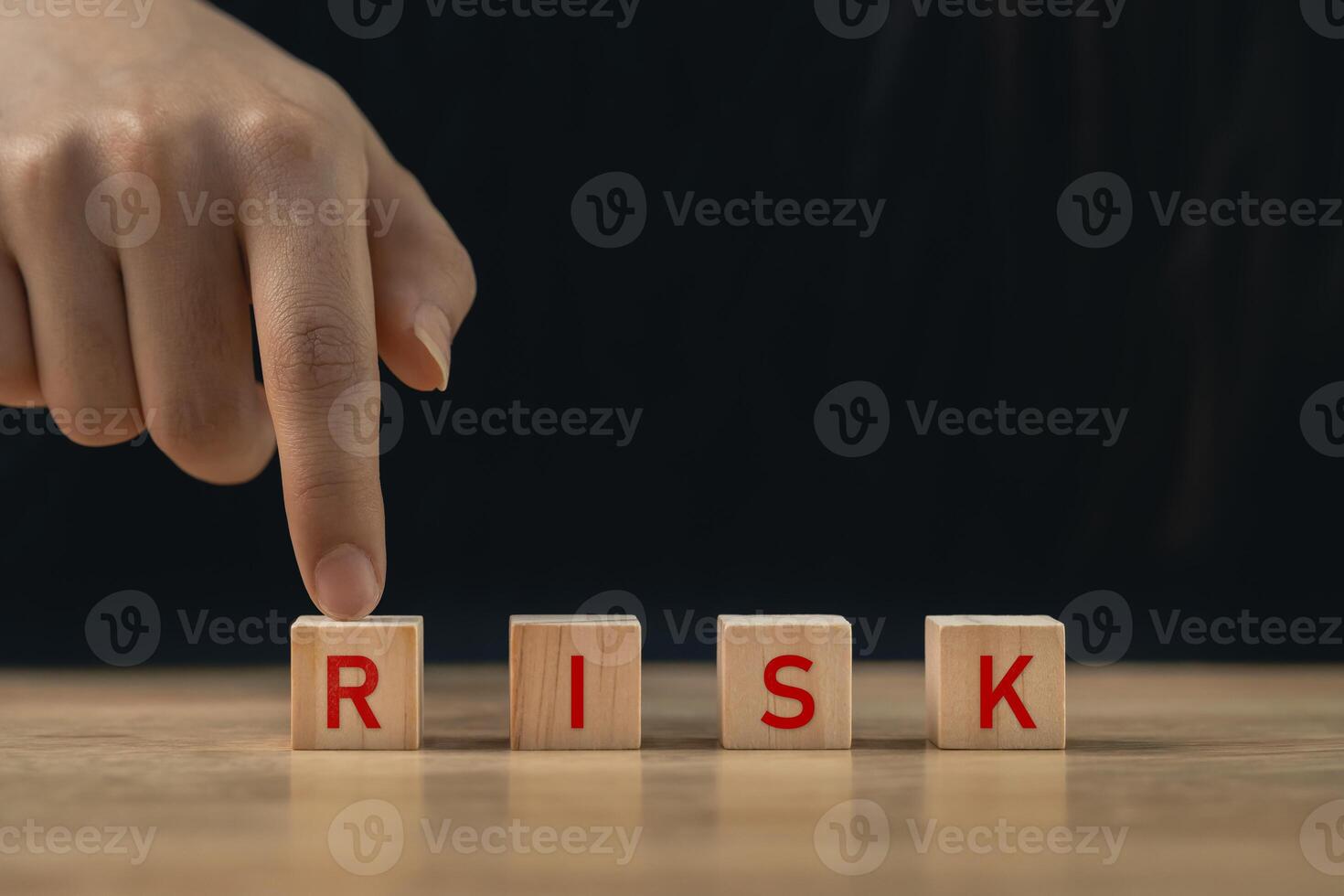 Focused Hand Pointing at Wooden Blocks Spelling Risk in a Dark Setting, Symbolizing Business Challenges and Decision-Making in Uncertain Environments photo