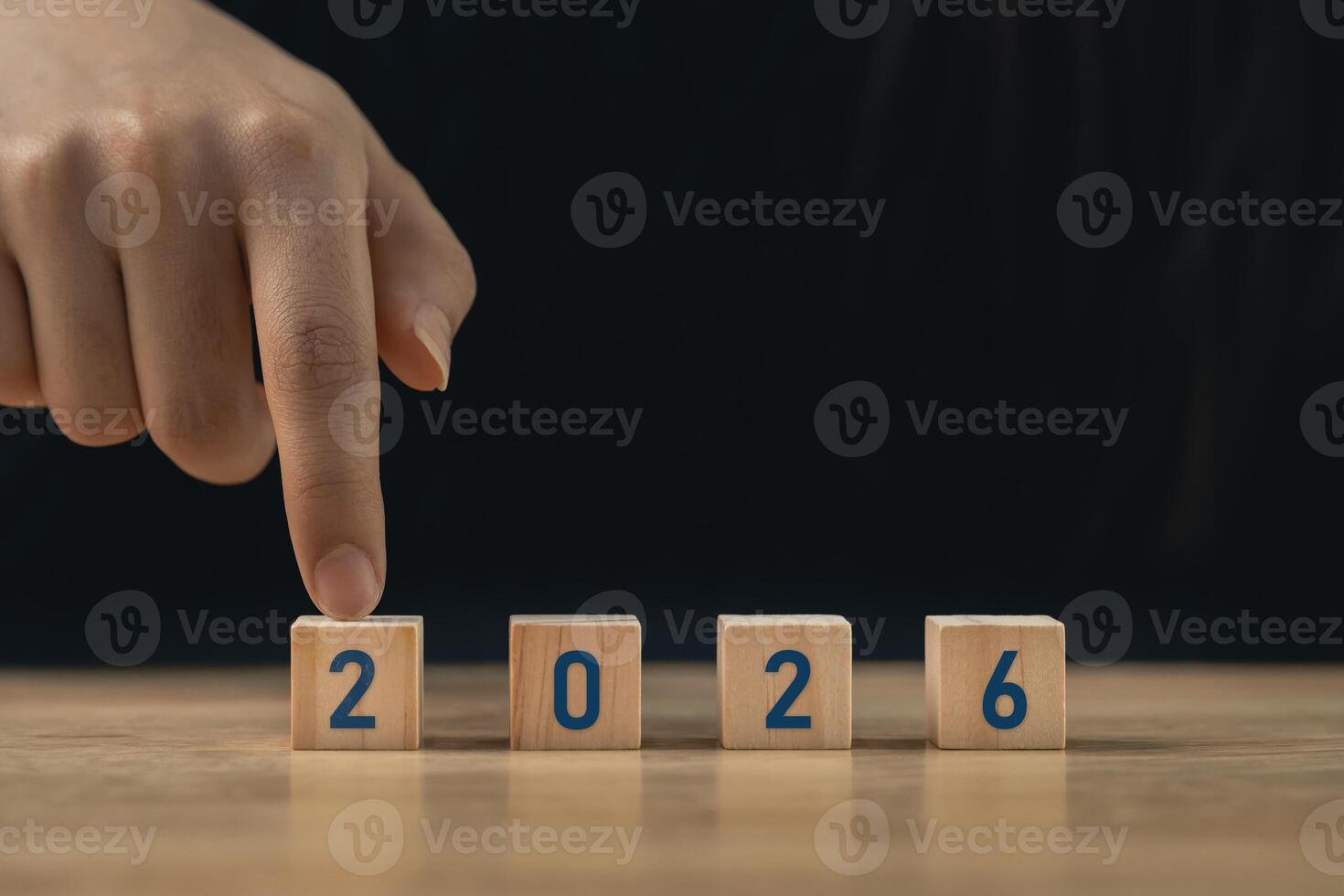 Hand arranging wooden blocks with numbers 2026 on a wooden surface symbolizing the approaching year and new beginnings for future planning and aspirations photo