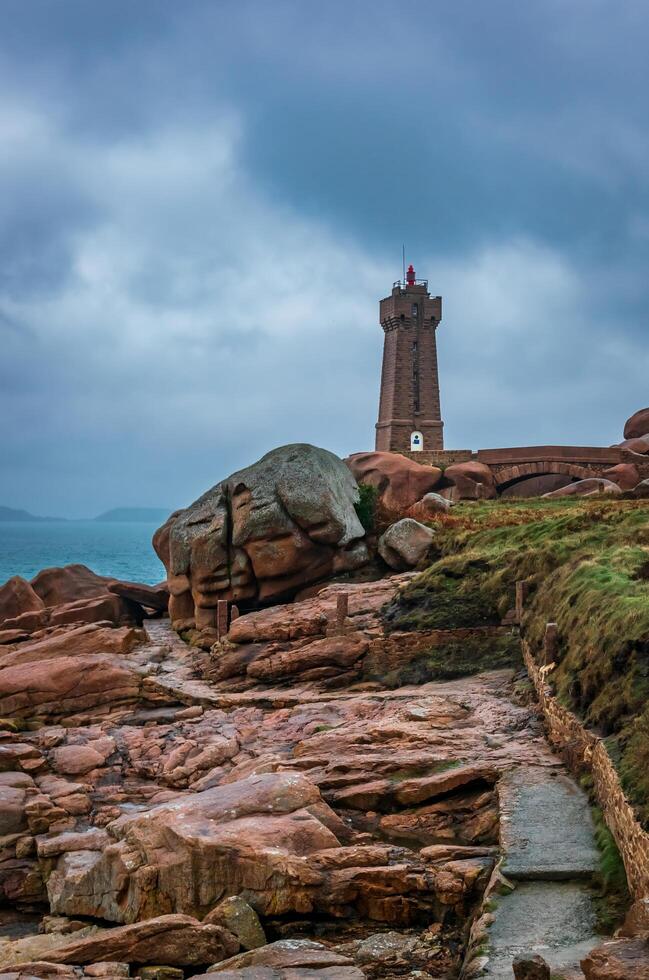 a lighthouse on a rocky shore with a dark sky photo