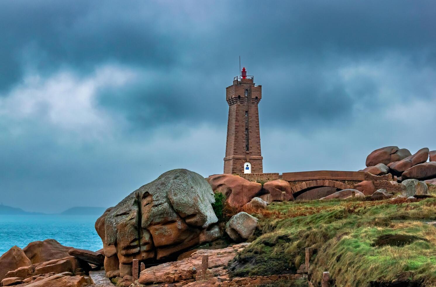 a lighthouse on the coast with a stormy sky photo