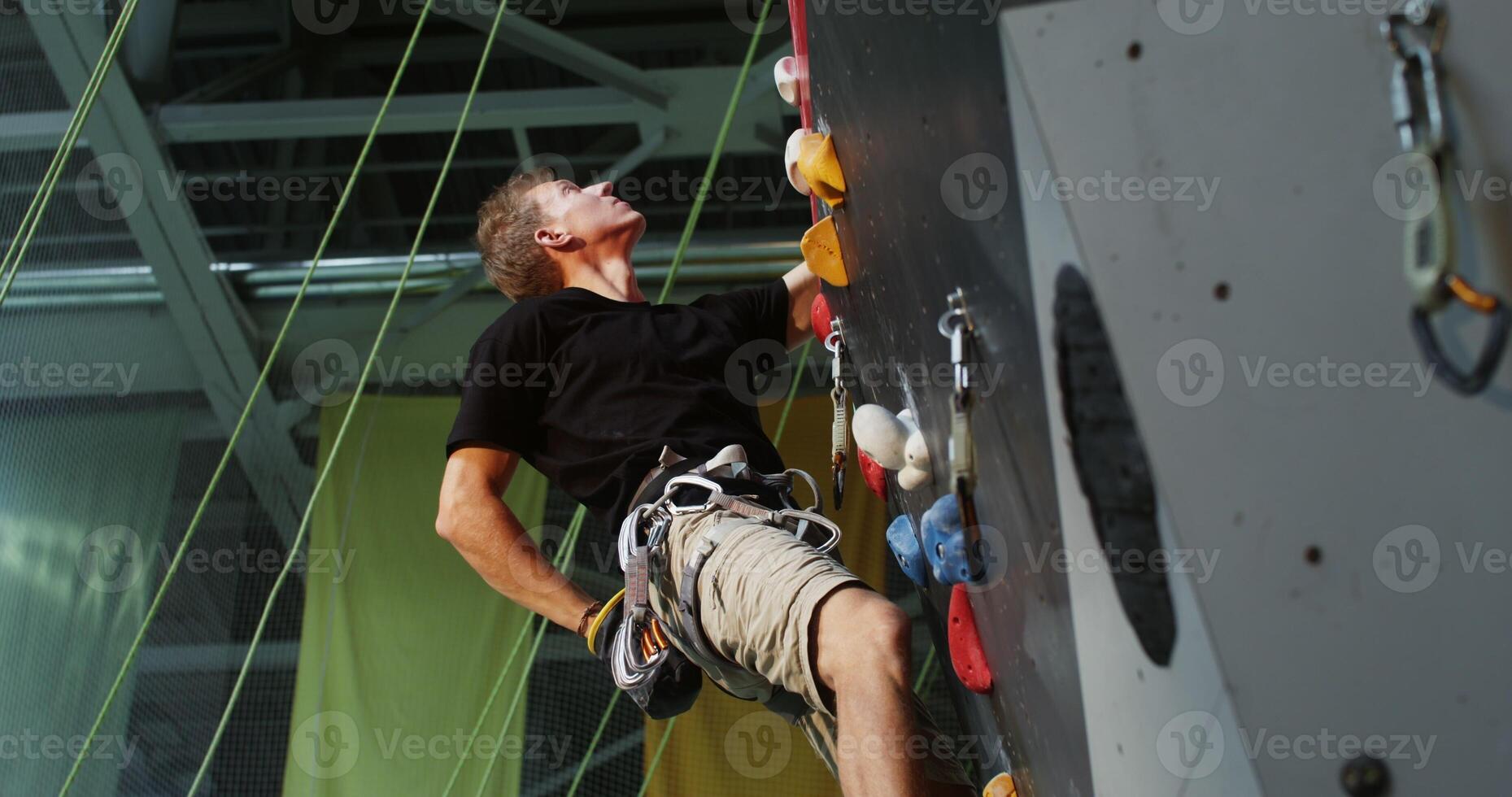 A man climbing on a rock wall in an indoor climbing gym photo
