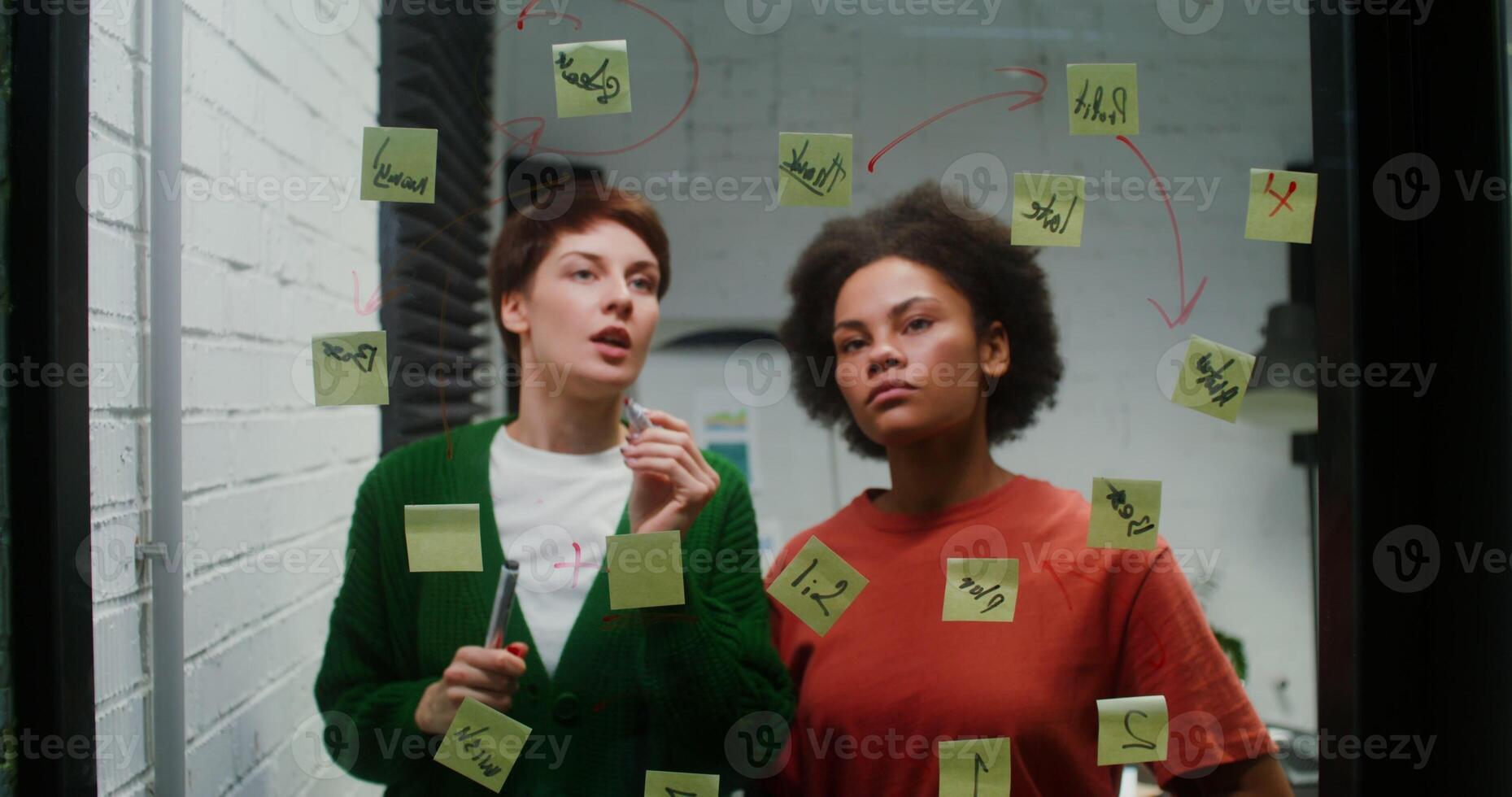 Two women standing in front of a window with sticky notes on it photo