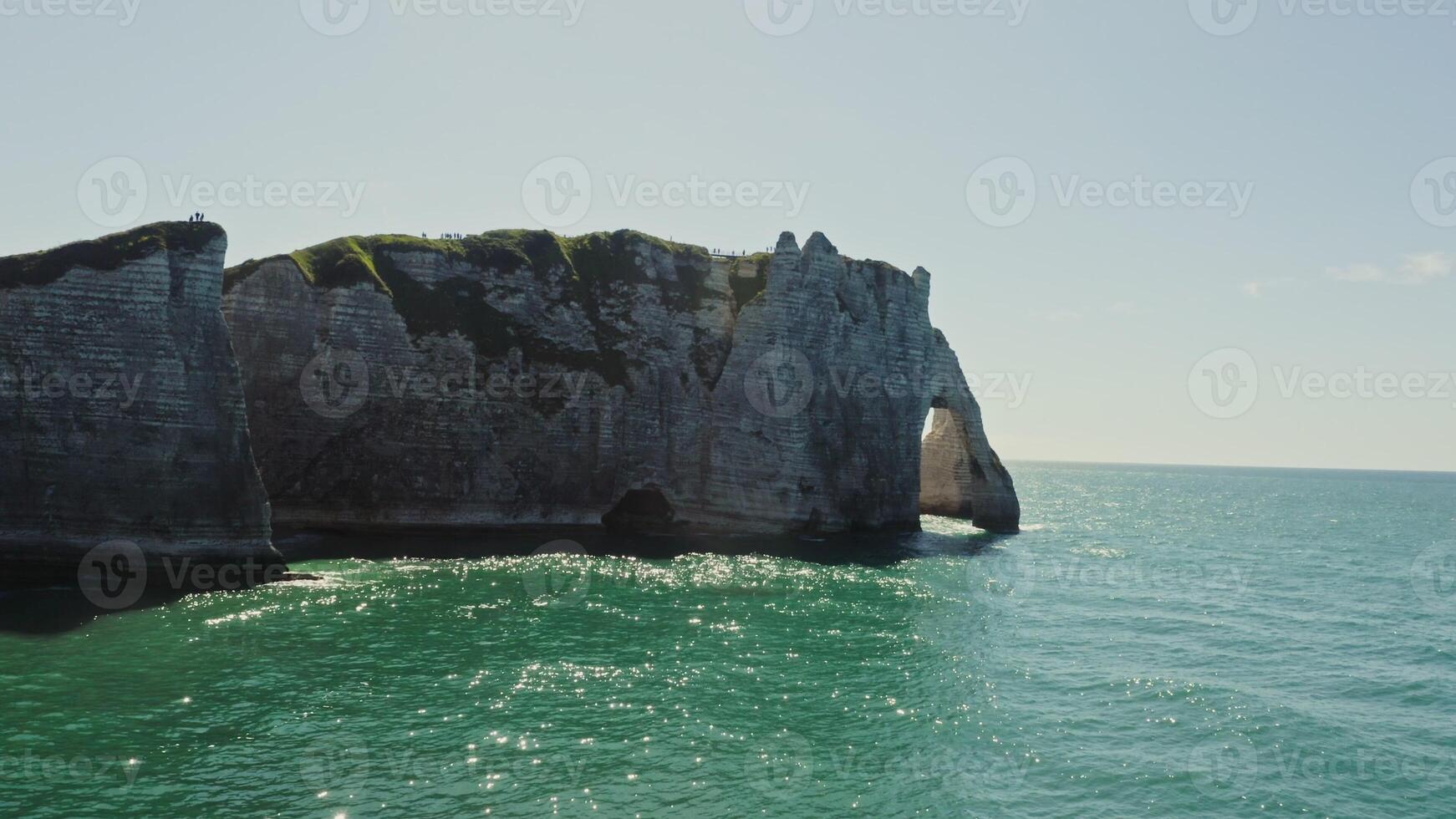 A large rock formation in the ocean with green water photo