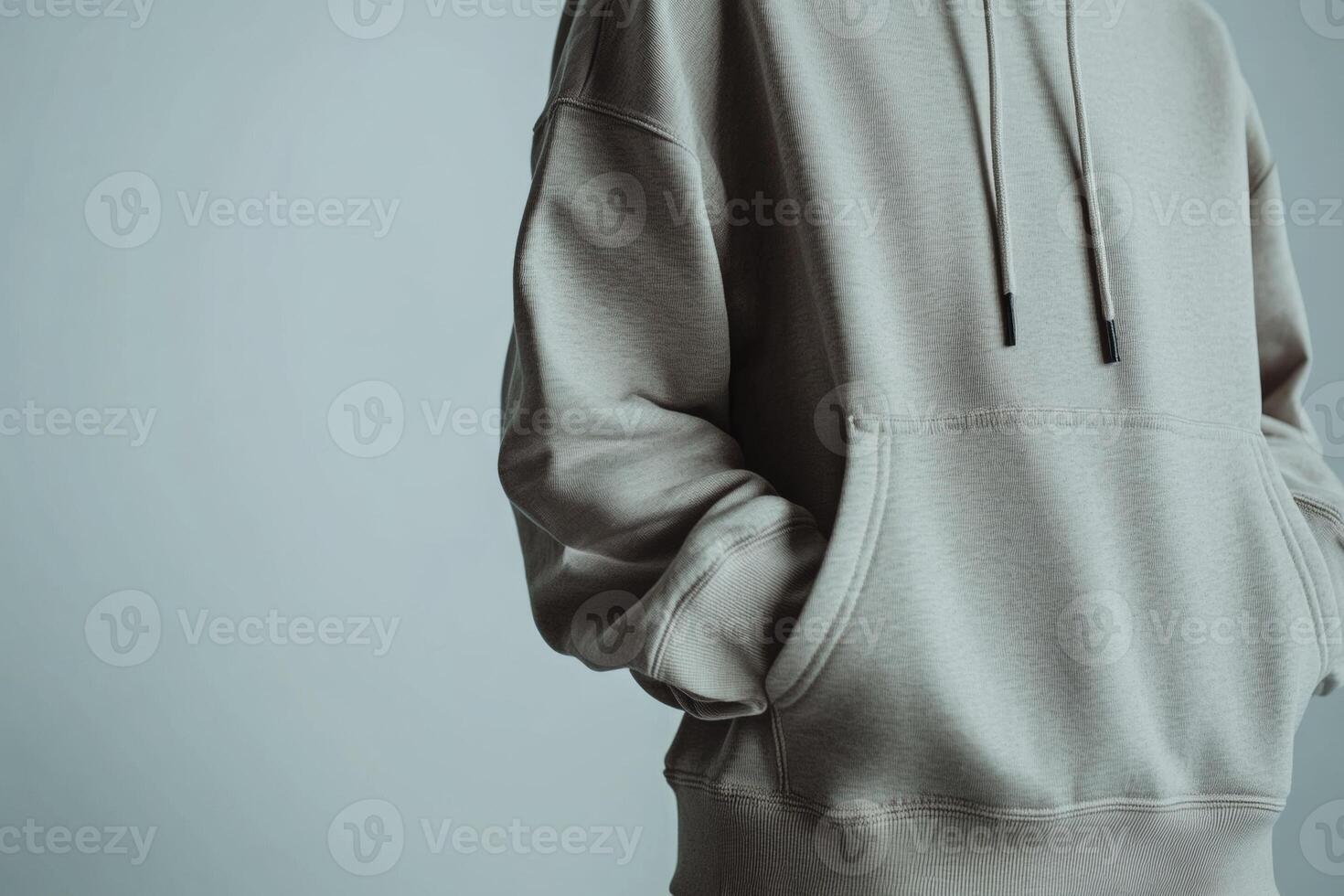 A man in a hoodie standing in front of a gray background photo