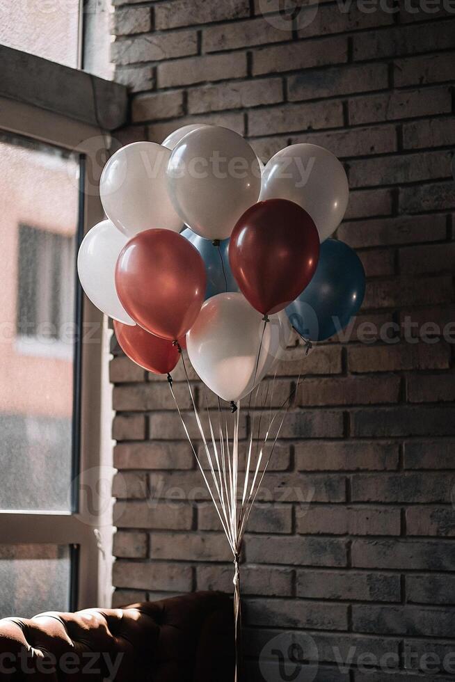 Colorful balloons grouped together in front of a rustic brick wall, creating a festive and vibrant atmosphere photo