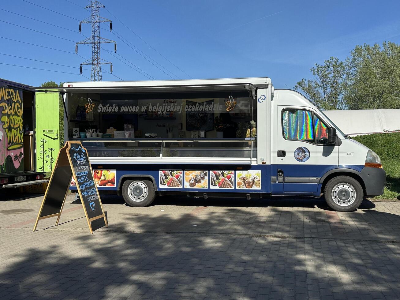 Warsaw, Poland - May 04, 2025 Food truck selling Belgian chocolate-covered fruits parked in a sunny outdoor location with clear blue sky photo