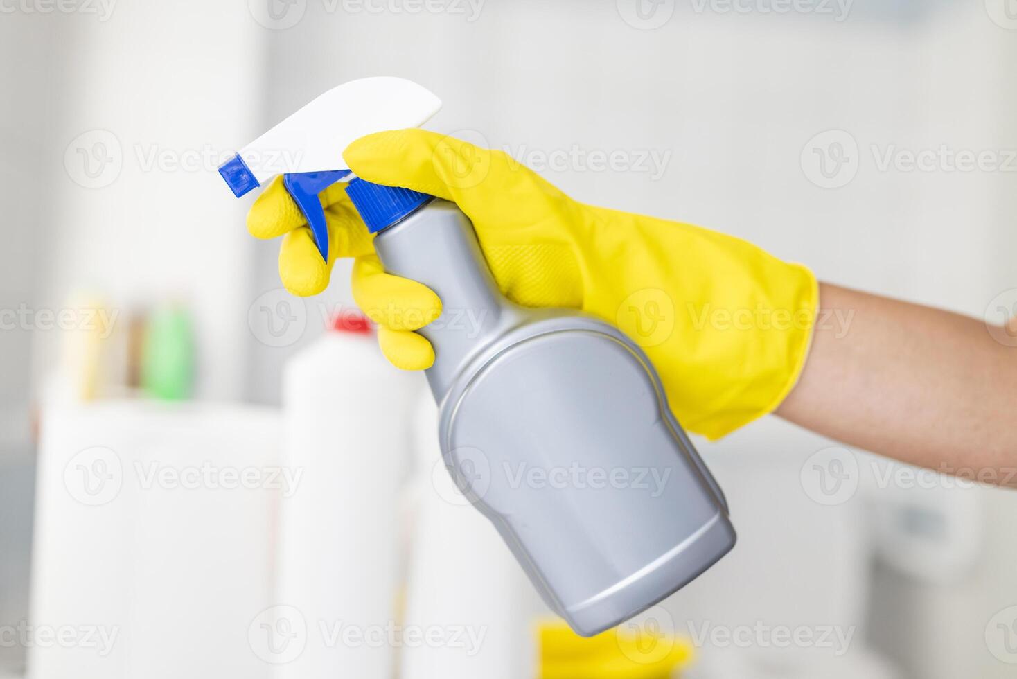 Hotel worker wearing rubber gloves cleaning bathroom with disinfectant and cleaning products ensuring hygiene and sanitation photo