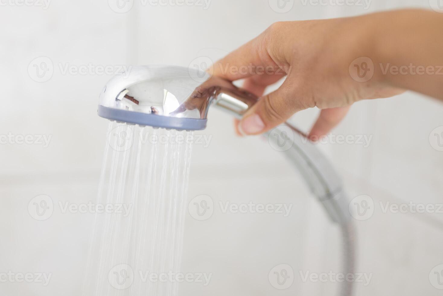 girl holding a shower with water in the bathroom for washing photo