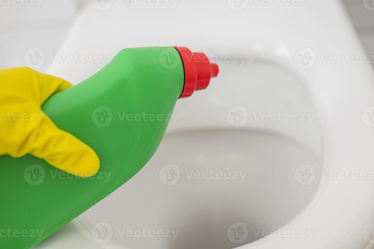 a girl in gloves cleans the toilet with detergent for disinfection and cleanliness photo
