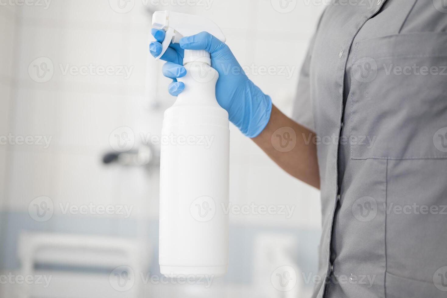 Girl hotel worker wearing rubber gloves cleaning the bathroom using disinfectant and cleaning products ensuring hygiene and sanitation photo