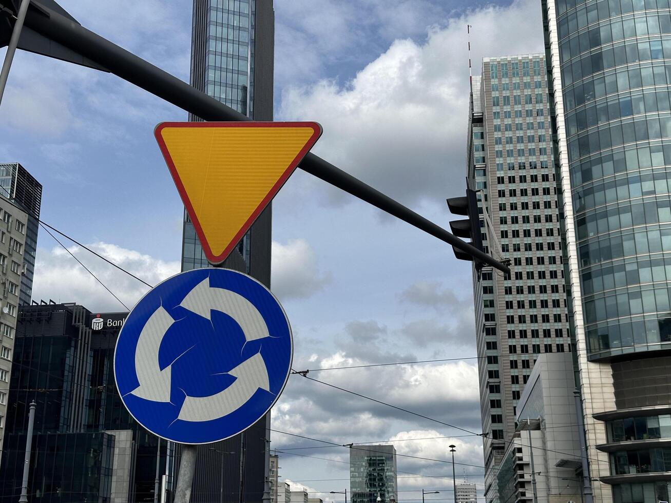 Warsaw, Poland - May 22, 2025 Traffic sign indicating roundabout with modern skyscrapers in the background, showcasing urban architecture and city life in a bustling metropolitan area photo