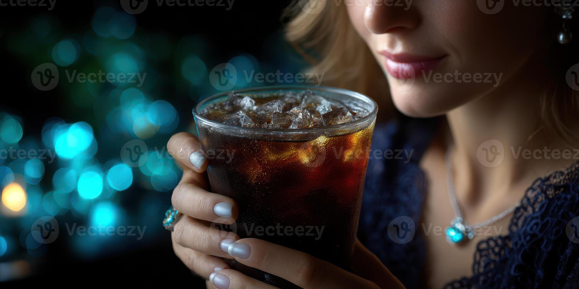 Elegant woman holding a glass of cold beverage with a sparkling background at a sophisticated evening gathering photo