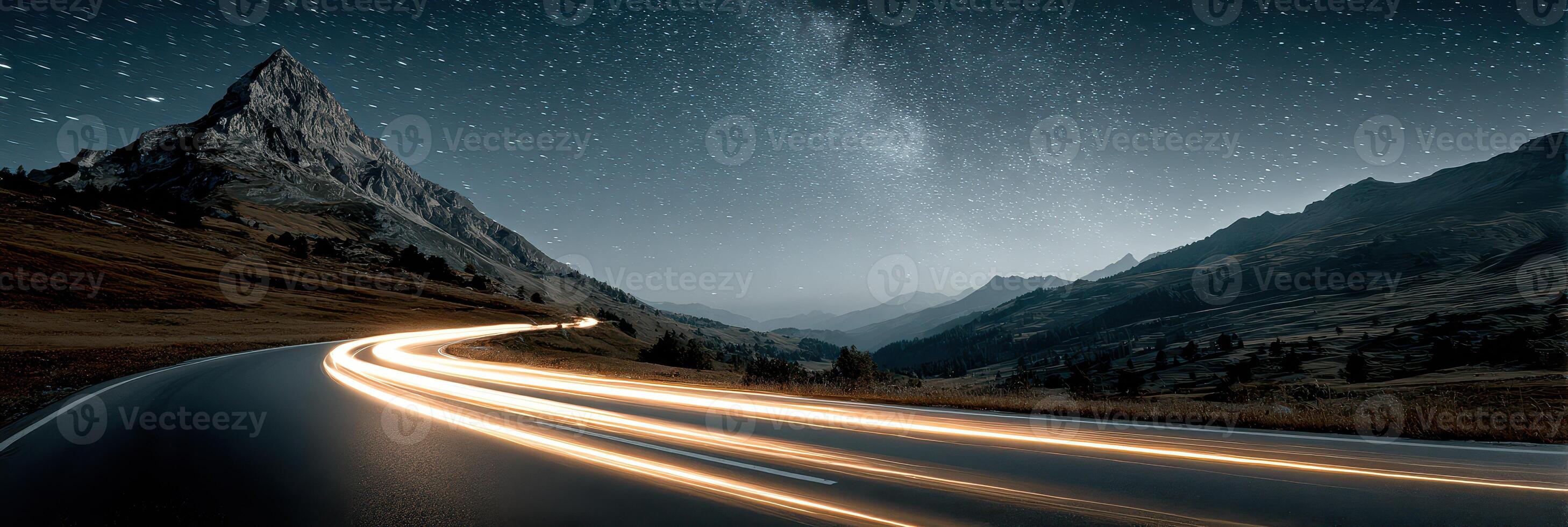 Nighttime mountain road captured with light trails and starry sky in a scenic landscape photo