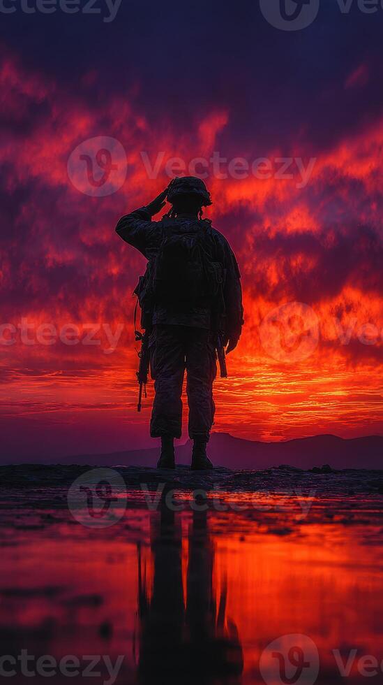 Soldier saluting at sunset with vibrant sky and reflections on the ground in a serene landscape photo