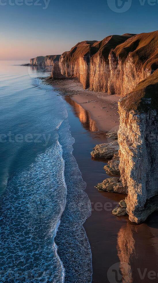 Majestic cliffs reflect in calm ocean waters during sunrise along the scenic coastline photo