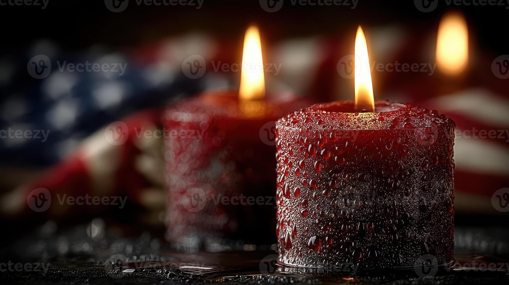 Red candles lit with droplets reflecting light against an American flag in a dimly lit setting photo