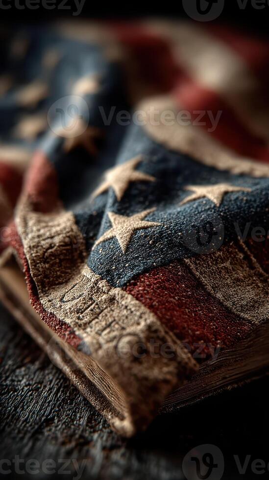 Old American flag draped over worn book with a rustic wooden background at sunset photo