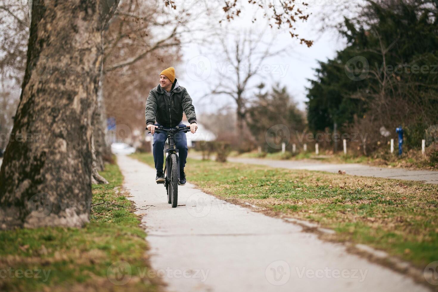 Man in jacket Riding Bike Down Street photo