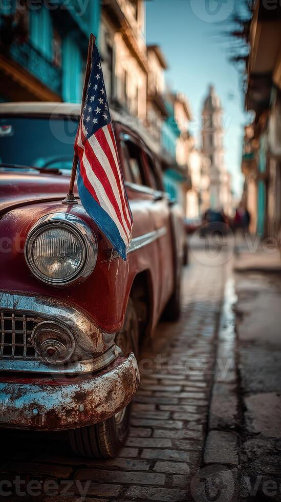 Classic car parked on a cobblestone street in Havana with an American flag during a sunny day photo