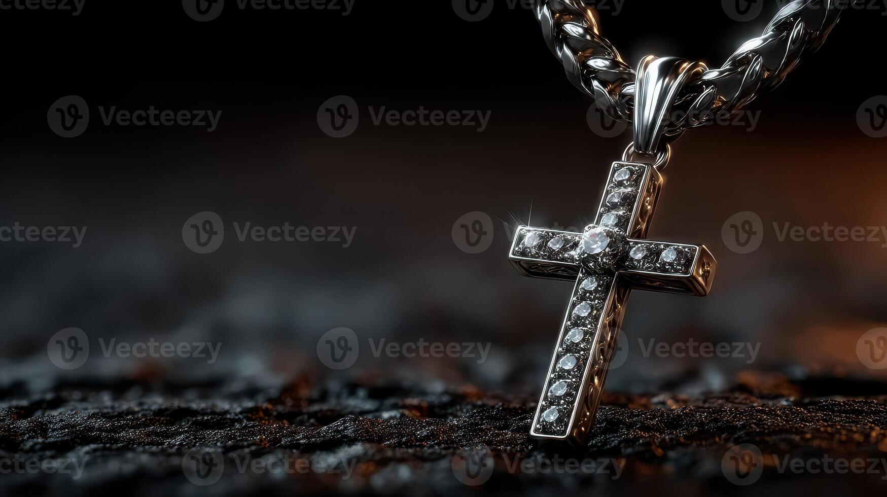 Silver cross necklace with intricate detailing resting on a textured surface illuminated by soft light photo