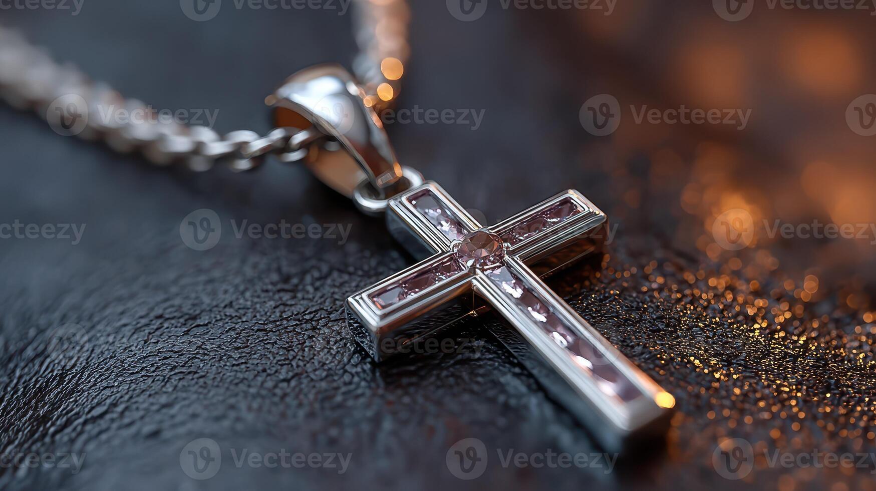 Silver cross pendant resting on a dark textured surface, showcasing intricate details and glimmering accents during soft lighting photo