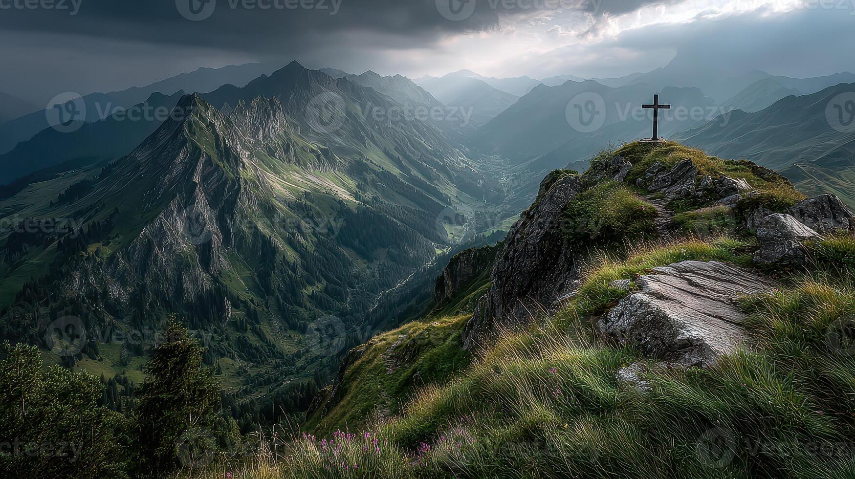 Mountain cross overlooks a valley under dramatic clouds in the late afternoon photo