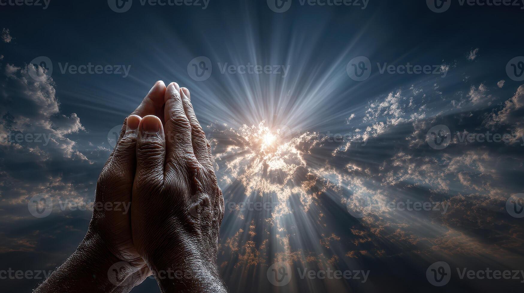 Hands raised in prayer against a dramatic sky filled with clouds and rays of sunlight during a serene moment of reflection photo