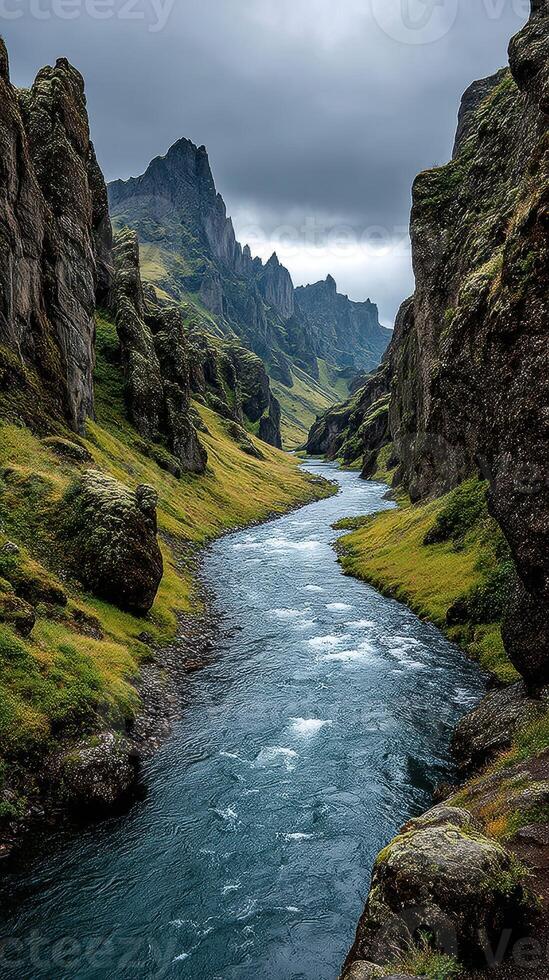 Majestic Icelandic landscape showcasing river flowing through rugged cliffs under a cloudy sky photo