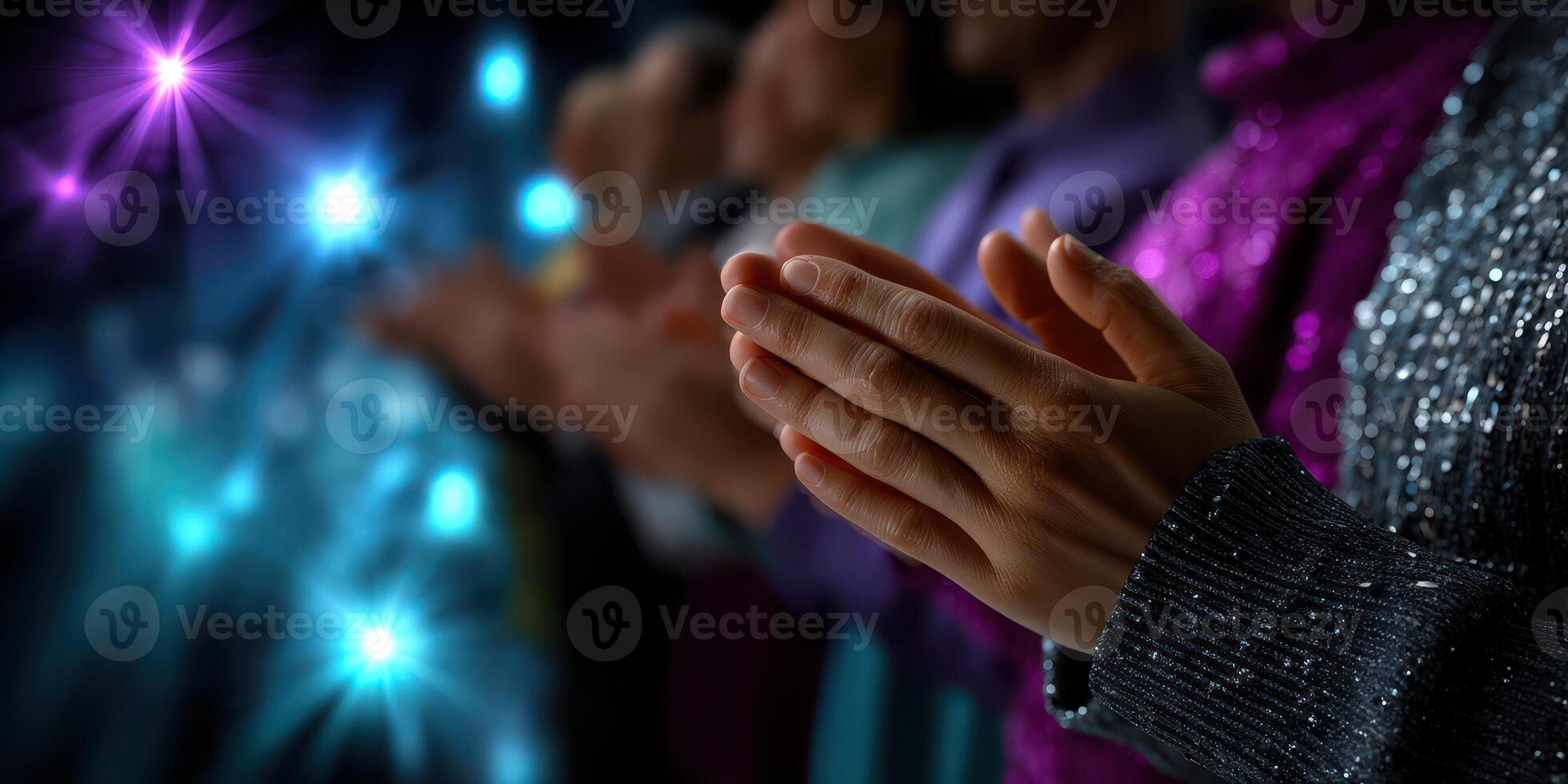 Audience members clapping in a dimly lit venue during a performance with colorful lights photo