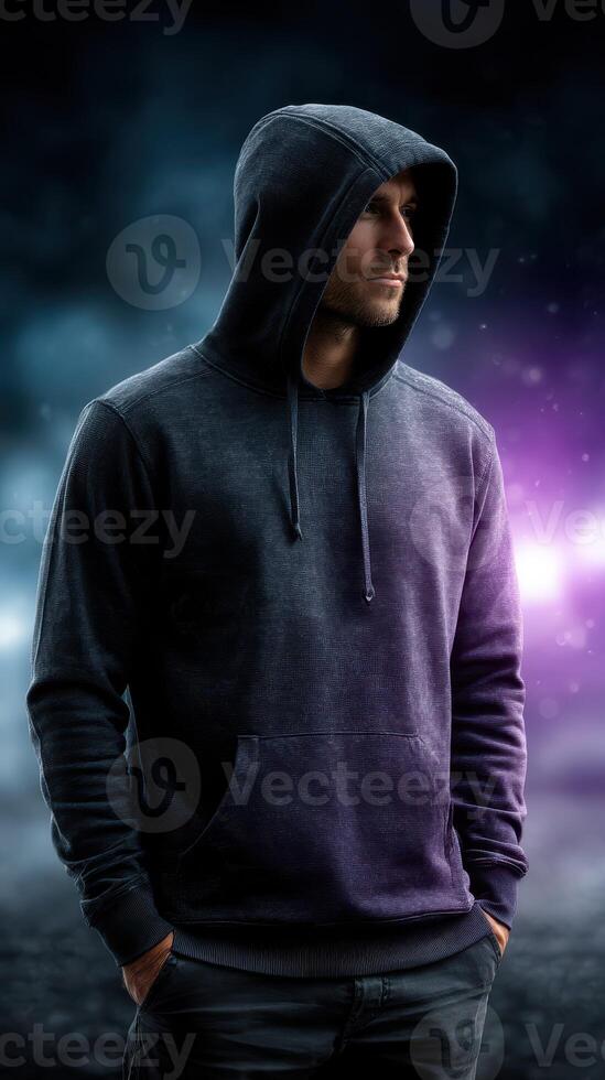 Man in hooded sweatshirt stands confidently against a dramatic, colorful background at night photo