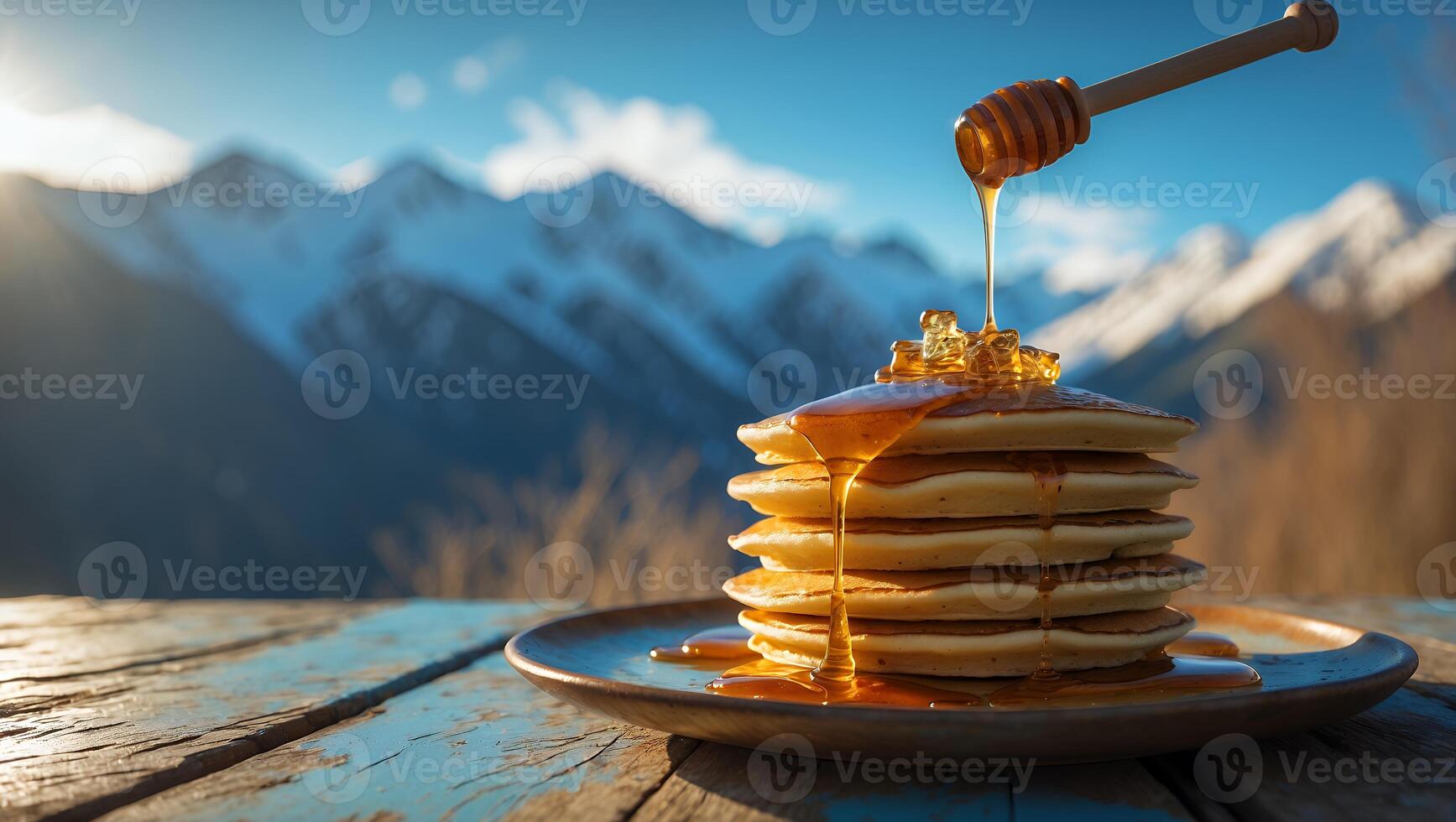Stack of Pancakes Being Drizzled with Honey Against a Mountain Backdrop photo