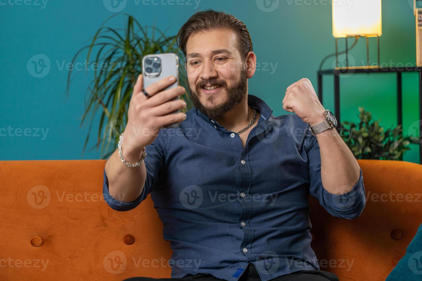 Lebanese man use smartphone celebrating winning, lottery jackpot goal achievemen, good news, victory photo