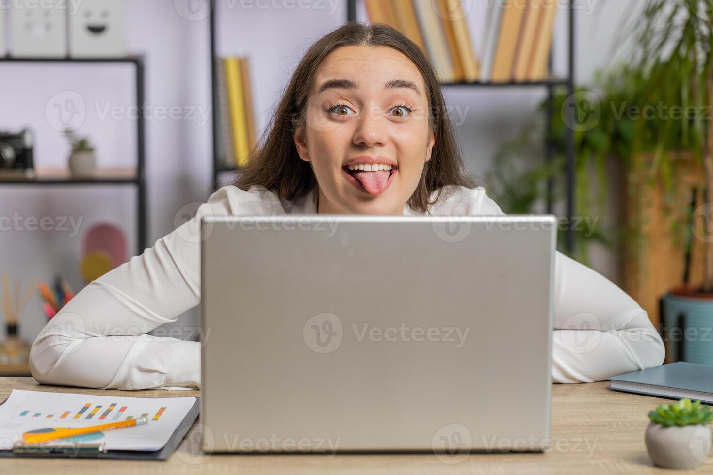 Office businesswoman hiding behind laptop computer making funny silly face fooling around disrespect photo