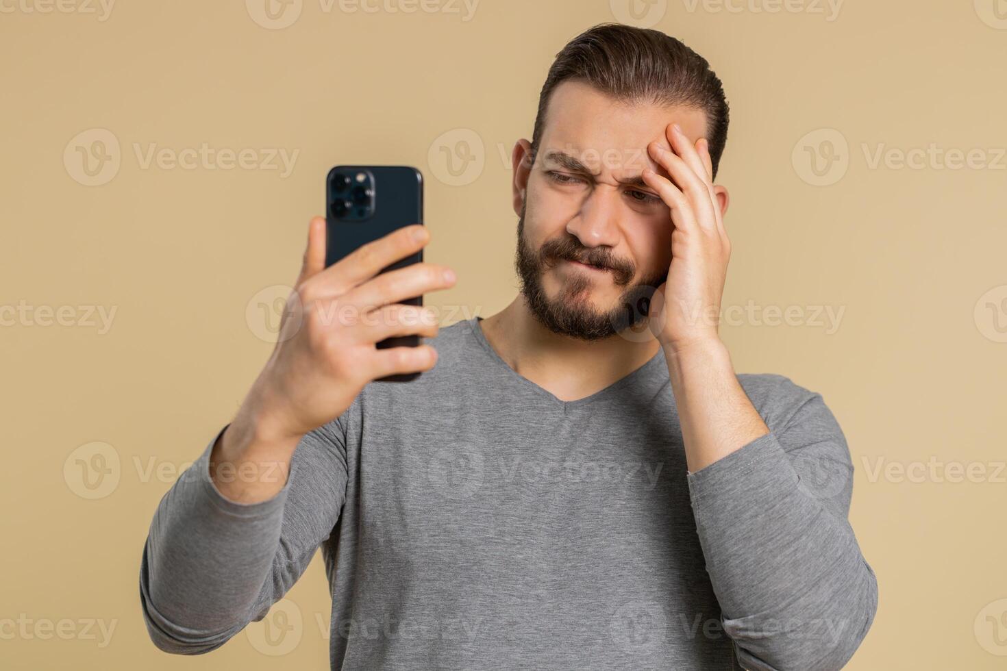 Young man use smartphone typing browsing loses becoming surprised sudden lottery result bad fortune photo