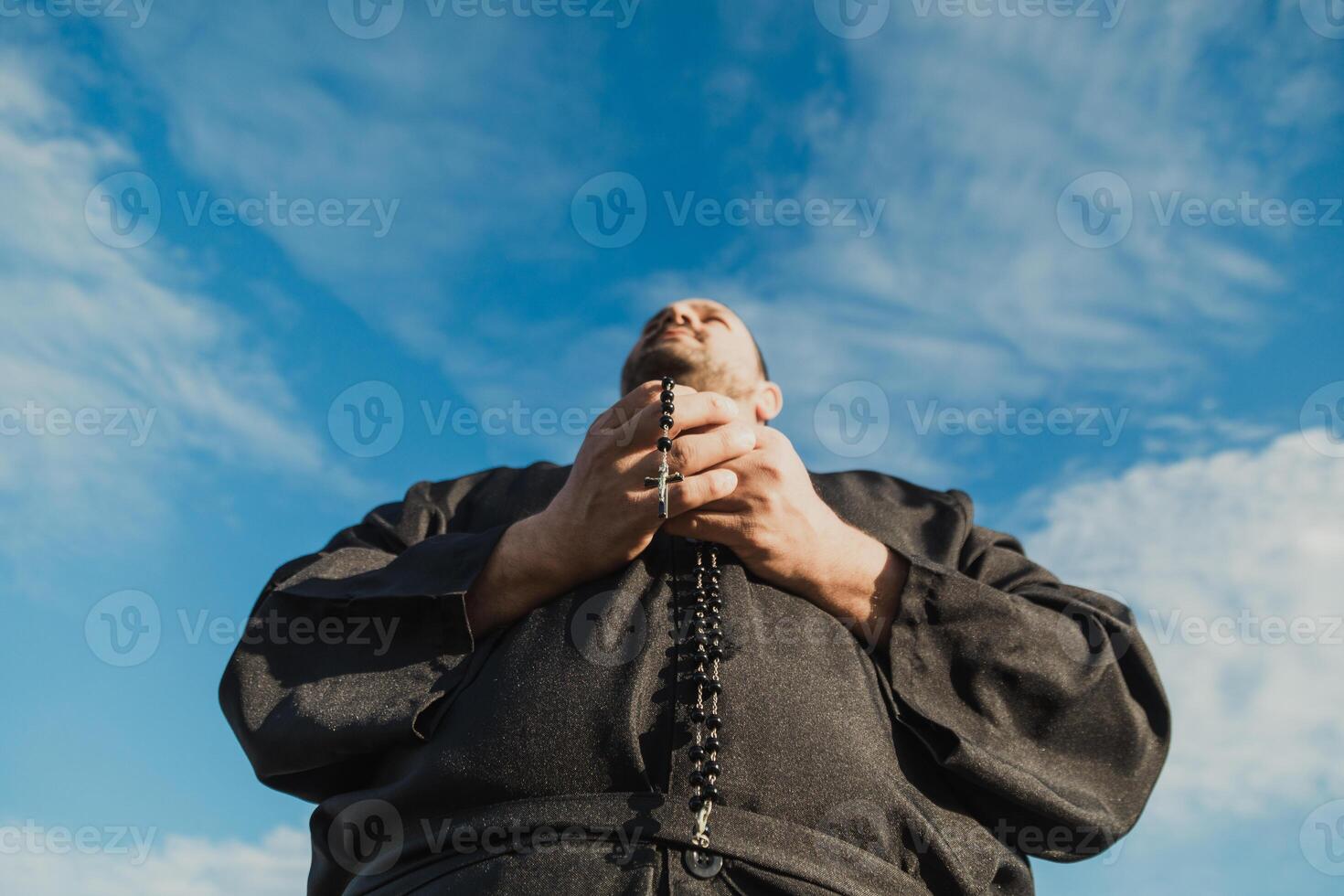 Hands Of A Priest Holding Jesus Crucifix While Praying photo