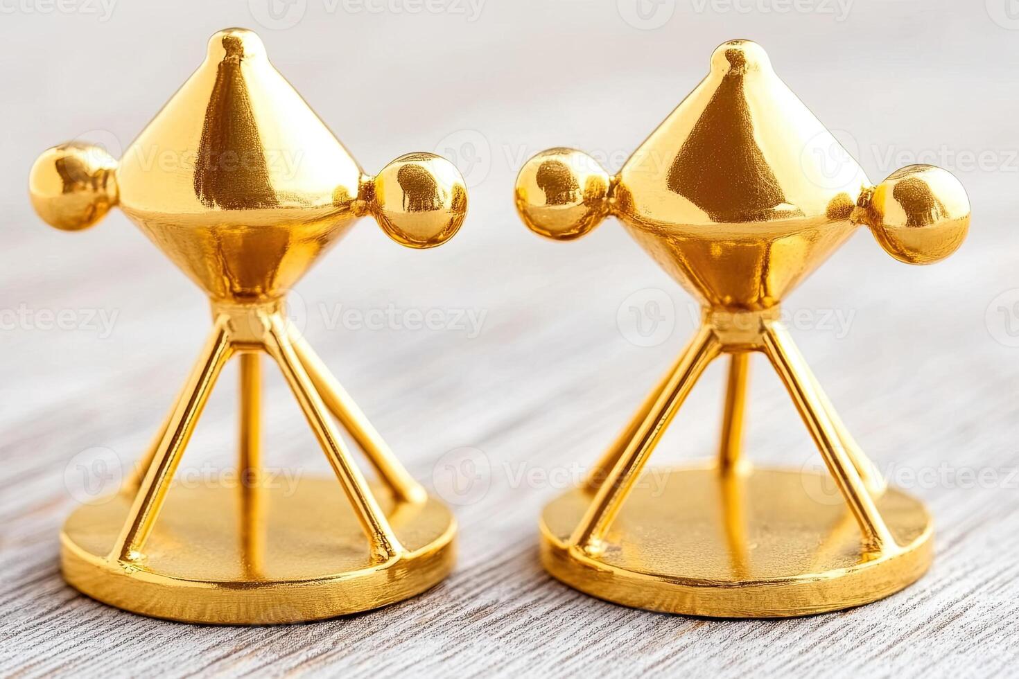 Two gold-plated miniature atomic models on a light wooden surface photo