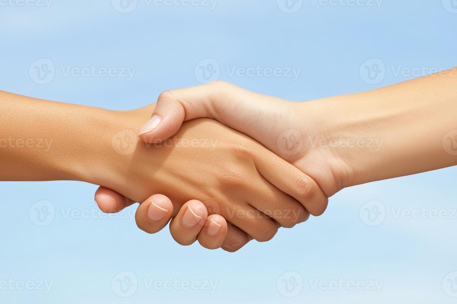 Two hands clasped in a friendly handshake against a clear sky photo