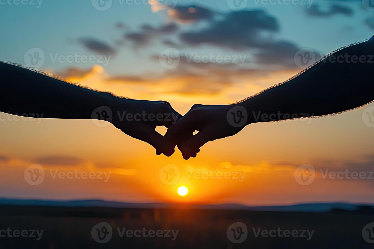 Silhouetted hands clasped at sunset photo