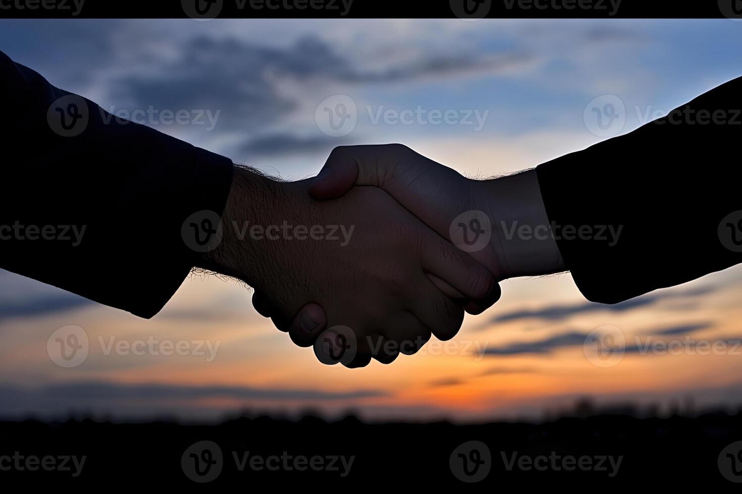 A handshake at sunset. Two people shaking hands against a beautiful sunset backdrop photo