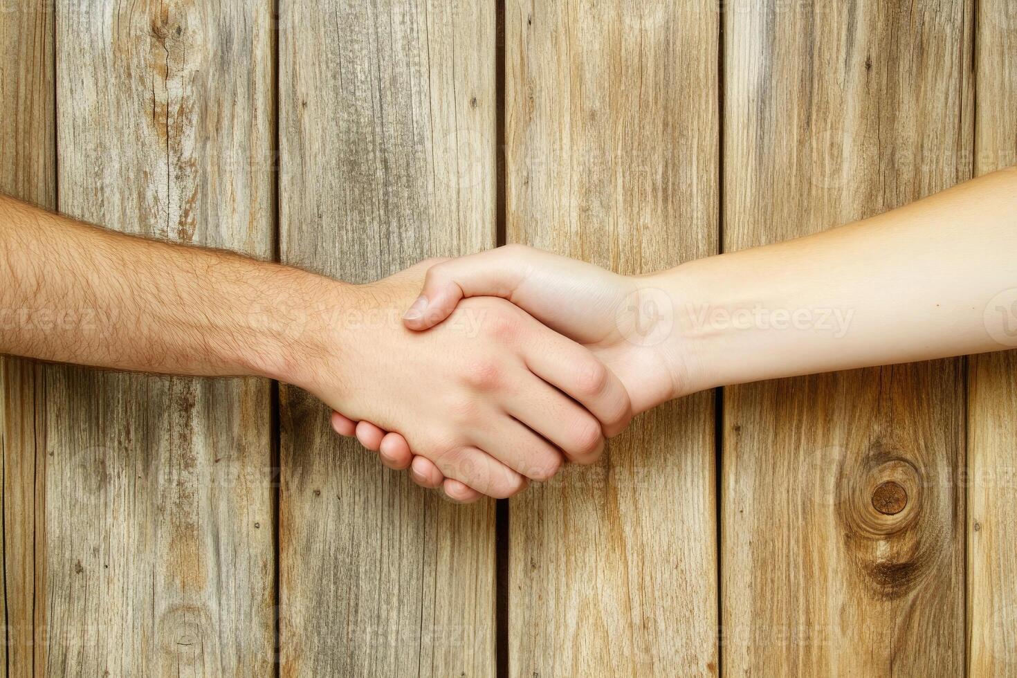 Two hands shaking, signifying a partnership or agreement, against a weathered wooden background photo