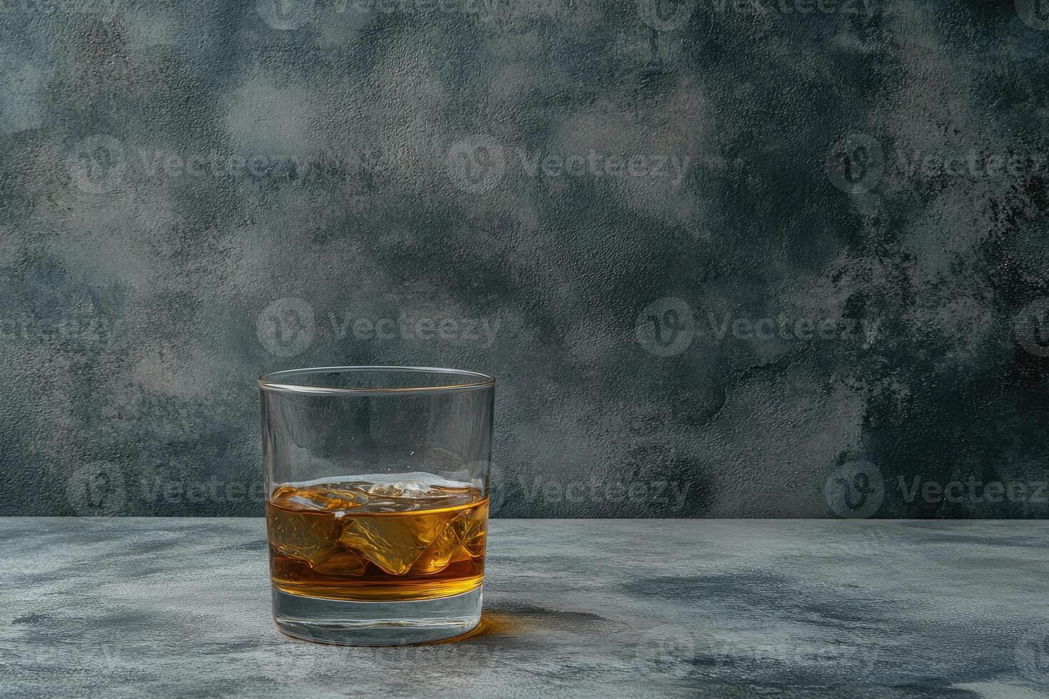 Single-glass of amber liquid with ice cubes on a table photo