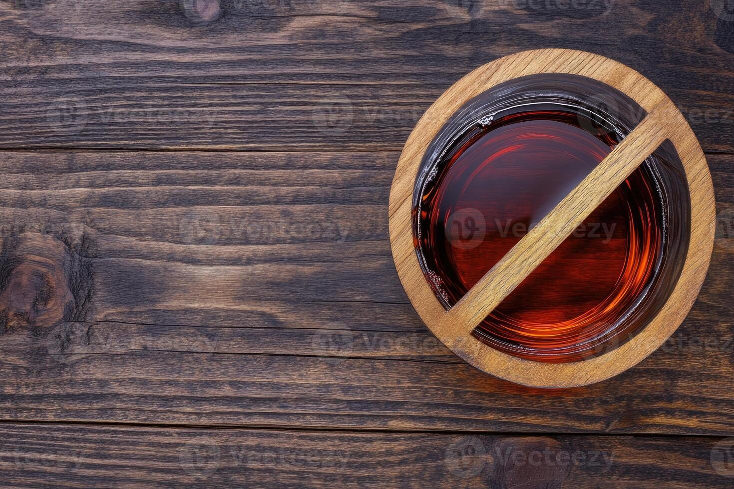 Amber liquid in a wooden bowl on a dark wooden table photo