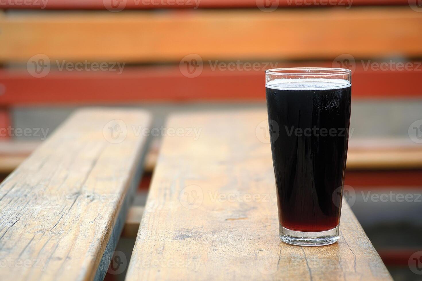 Dark drink in a glass on a wooden table photo