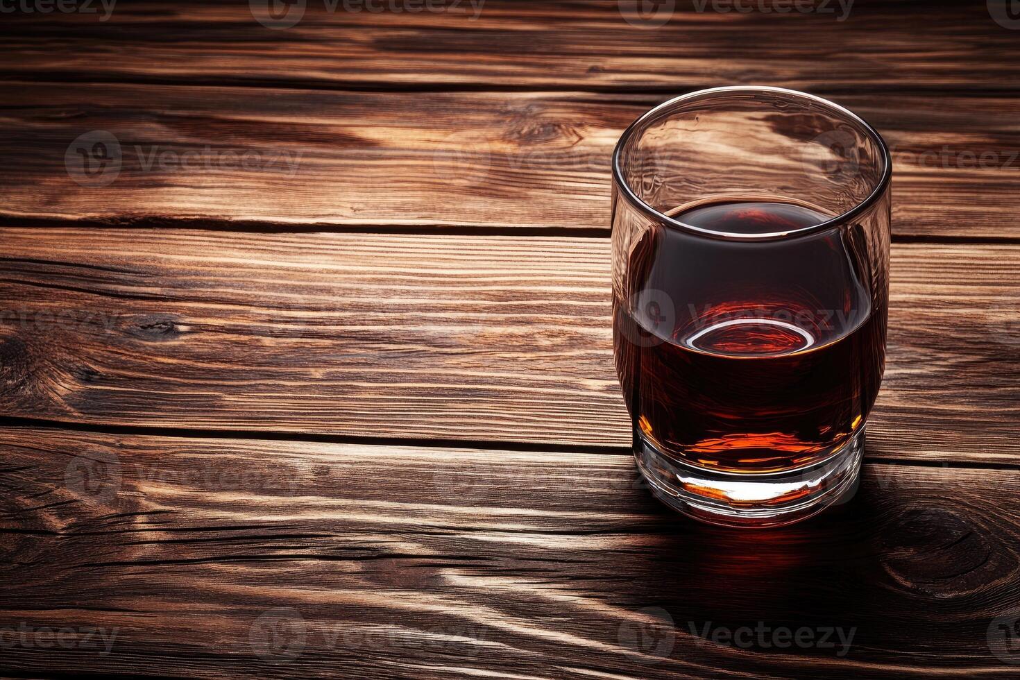 Dark spirit in a glass on a wooden table photo